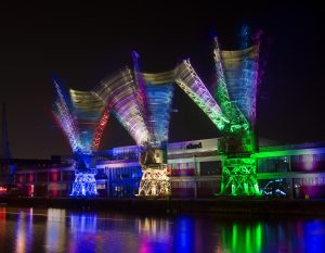 Composite image capturing the movement of three of BristolÕs iconic dock cranes, lit up for Crane Dance Bristol, a one-off performance from Laura Kriefman, from the Pervasive Media Studio at the Watershed arts centre, Bristol. 10,000 people gathered to watch as Laura Kriefman choreographed the synchronised cranes, at the headline event at the cityÕs Docks Heritage Weekend, a weekend of activities exploring the history and working life of the old City Docks. 3 Oct 2015