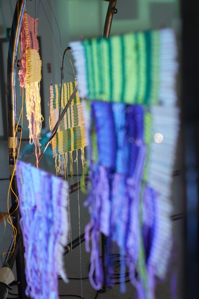 Woven tapestries hanging off a steel frame. 